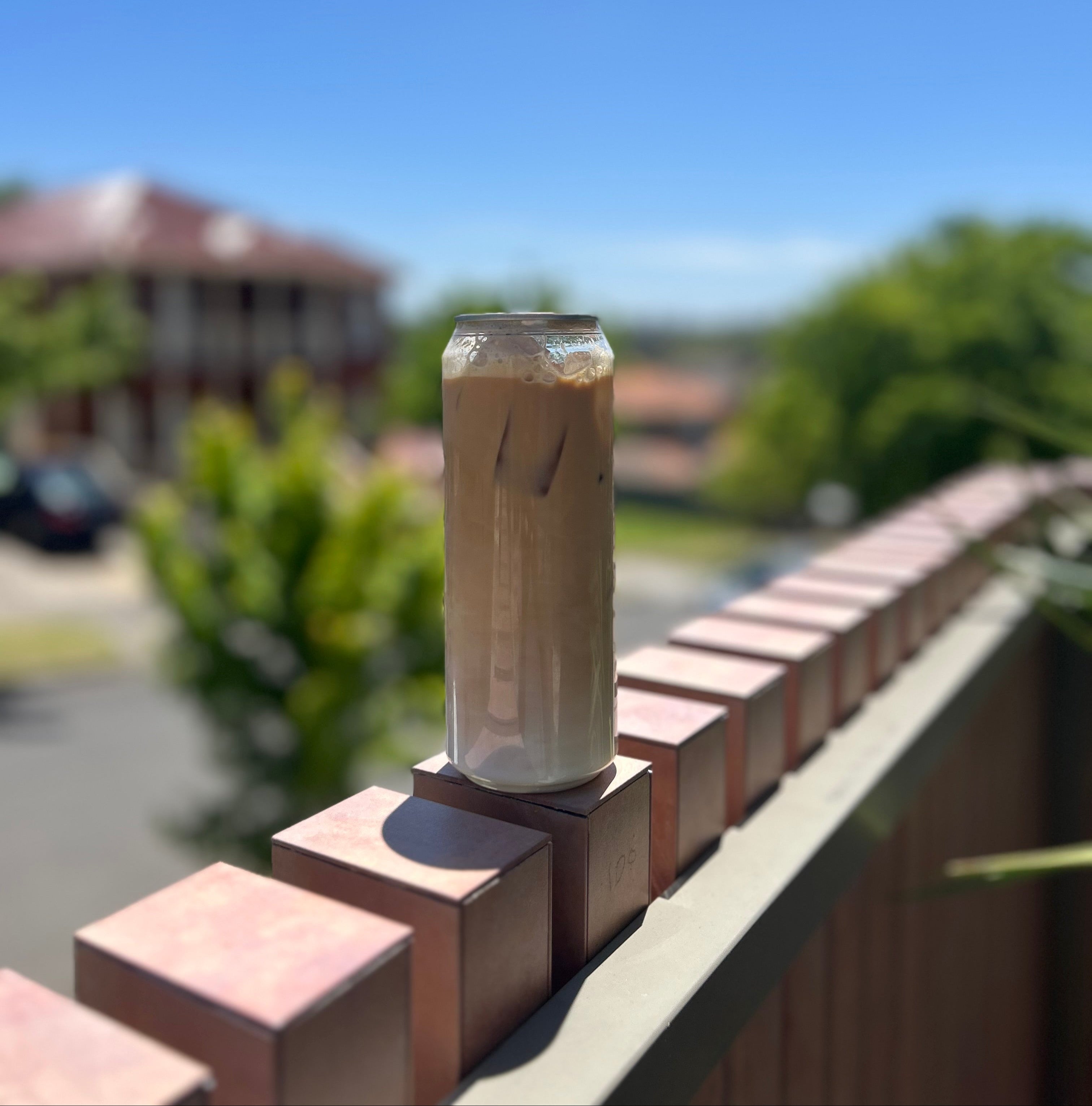 Glass of iced coffee on a ledge with a blurred outdoor background